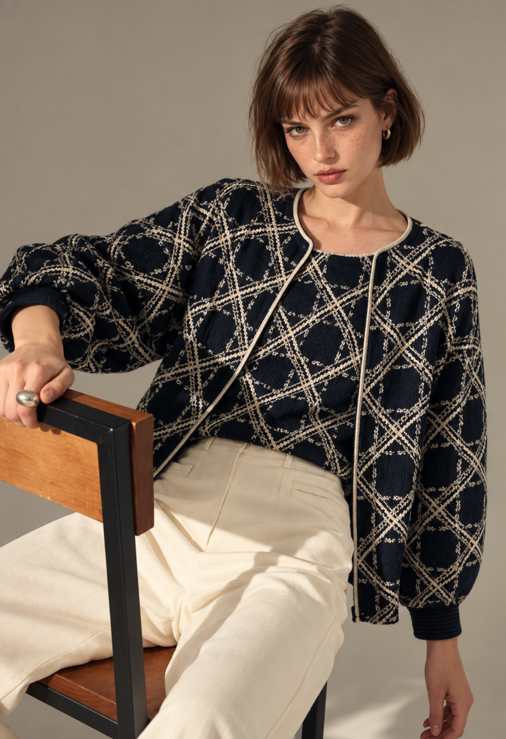 Model in a dark patterned blouse and cream trousers