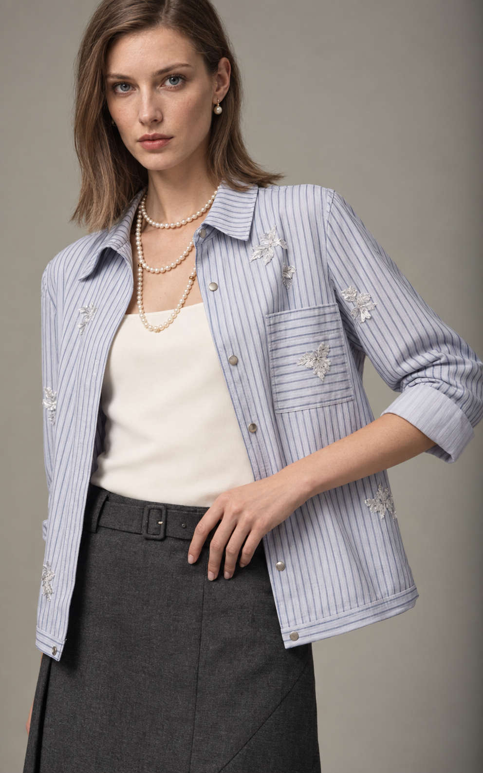 Model in a blue pinstripe overshirt, pearl necklace and charcoal skirt