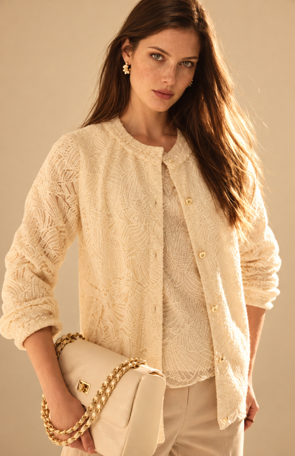 Model in a textured ivory jacket with a cream handbag